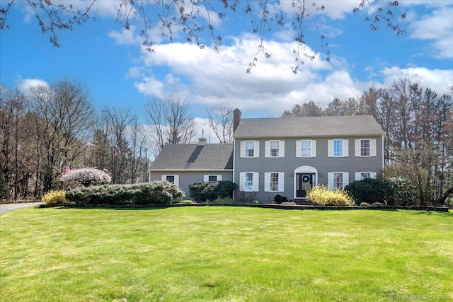 colonial-style house with a chimney and a front yard