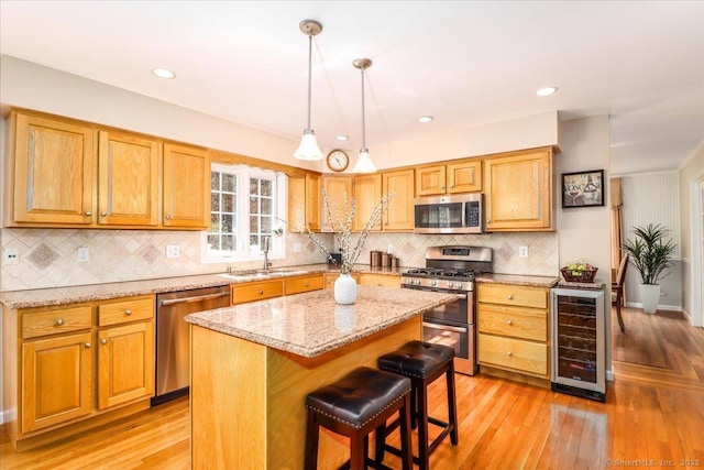 kitchen with wine cooler, light stone countertops, a sink, light wood-style flooring, and stainless steel appliances