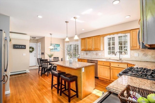 kitchen featuring a wall unit AC, tasteful backsplash, baseboard heating, a sink, and stainless steel appliances