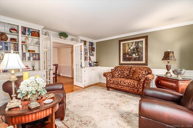 living room featuring french doors, ornamental molding, and wood finished floors