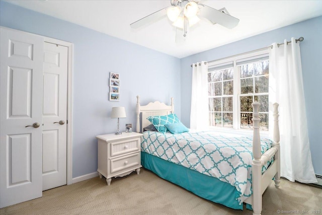 bedroom with a ceiling fan, baseboards, and light colored carpet