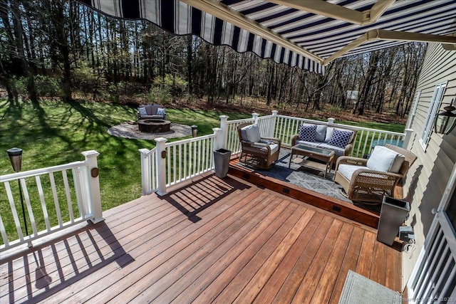 wooden deck featuring an outdoor living space with a fire pit, a view of trees, and a yard