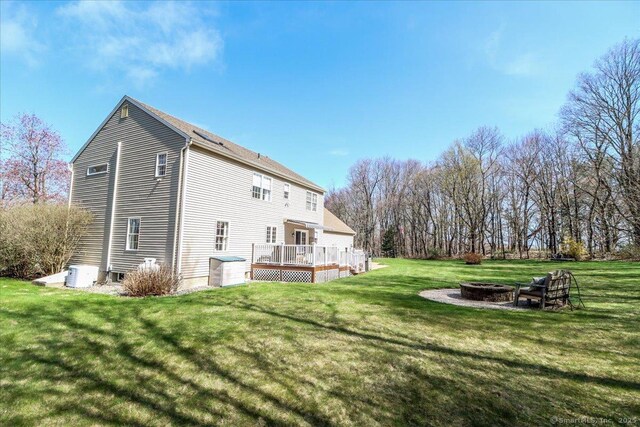 rear view of house with a lawn, a deck, and an outdoor fire pit