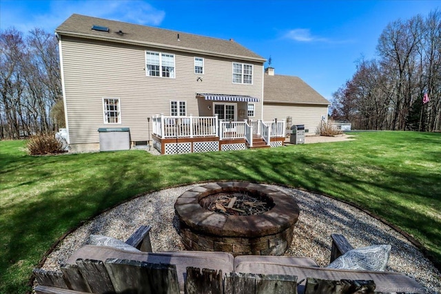 rear view of property featuring a wooden deck, a yard, and an outdoor fire pit
