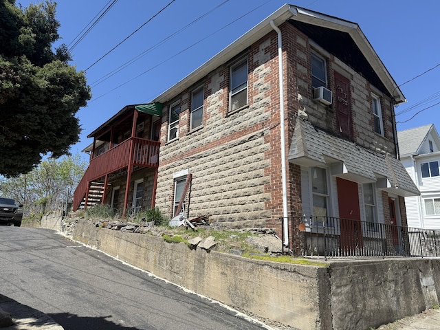 view of property exterior with stairway, brick siding, and cooling unit