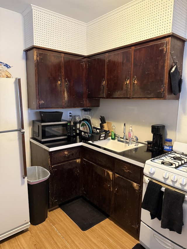 kitchen featuring a sink, light wood-type flooring, white appliances, and dark brown cabinets