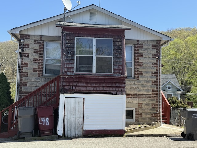 rear view of property with stairs and brick siding