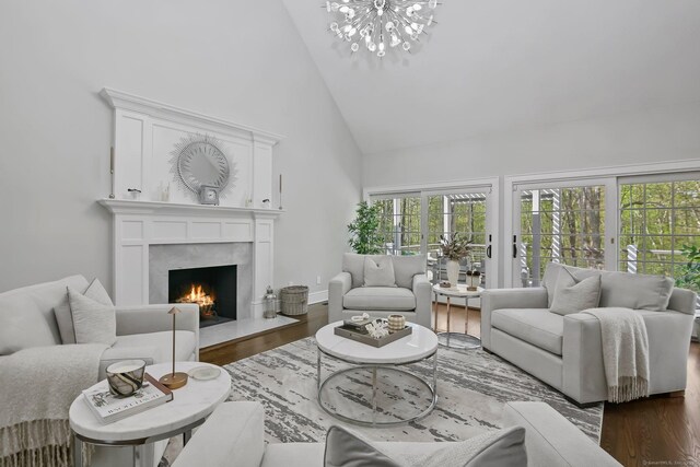 living room featuring high vaulted ceiling, a chandelier, dark wood-style floors, and a high end fireplace