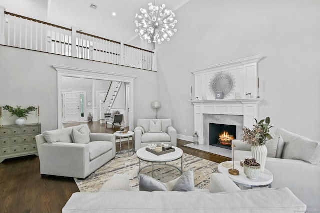 living area featuring dark wood-style floors, a high end fireplace, a high ceiling, and stairs