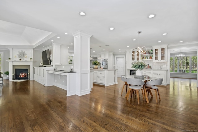 dining space with a glass covered fireplace, plenty of natural light, recessed lighting, ornamental molding, and a chandelier