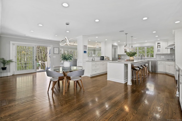 kitchen featuring under cabinet range hood, crown molding, a center island, stainless steel dishwasher, and white cabinets
