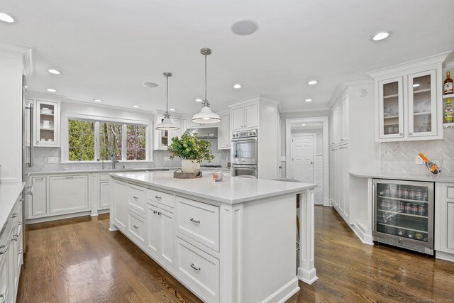 kitchen with wine cooler, double oven, a center island, decorative backsplash, and white cabinets