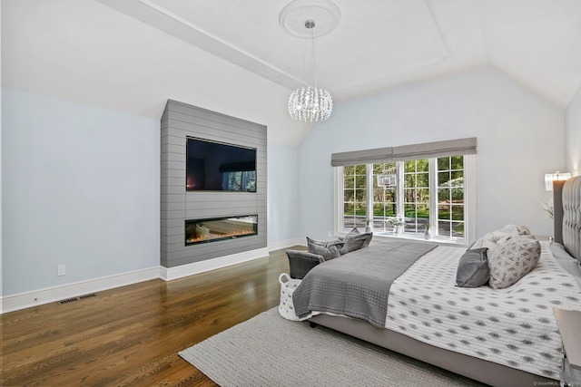 bedroom with wood finished floors, a large fireplace, a chandelier, lofted ceiling, and baseboards