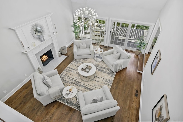 living room featuring wood finished floors, a high end fireplace, lofted ceiling, a chandelier, and baseboards