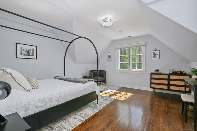 bedroom with wood finished floors, vaulted ceiling, and baseboards