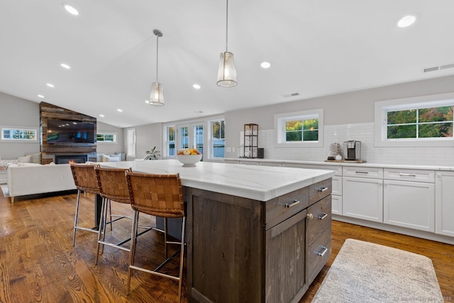 kitchen with white cabinets, visible vents, a kitchen breakfast bar, and a healthy amount of sunlight