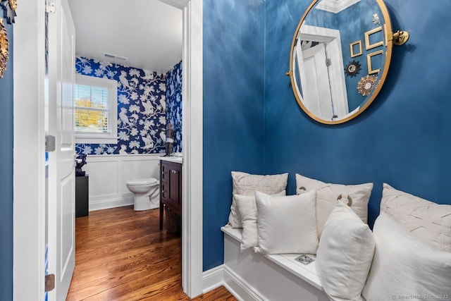 bathroom featuring toilet, wood finished floors, vanity, visible vents, and wainscoting