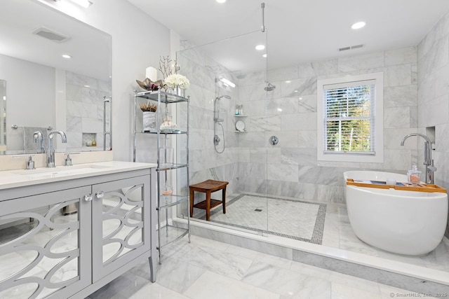 bathroom with marble finish floor, visible vents, a tile shower, vanity, and a freestanding bath
