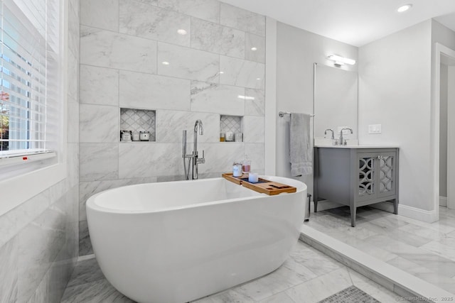 bathroom featuring vanity, tile walls, marble finish floor, and a freestanding tub