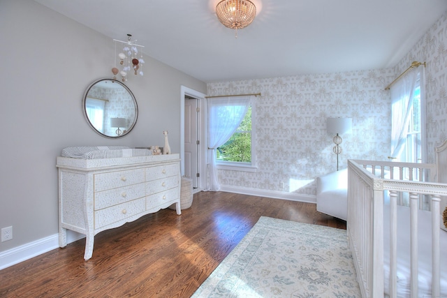 bedroom featuring baseboards, wallpapered walls, and wood finished floors