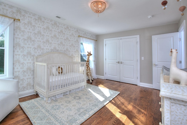 bedroom featuring baseboards, a closet, wallpapered walls, and visible vents