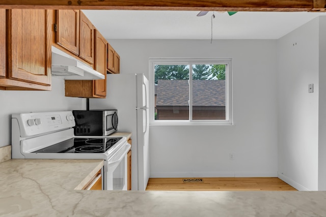 53 Cedar Knolls Dr Unit 53, Branford, CT 06405 - kitchen with white range with electric cooktop, under cabinet range hood, stainless steel microwave, brown cabinetry, and light wood finished floors