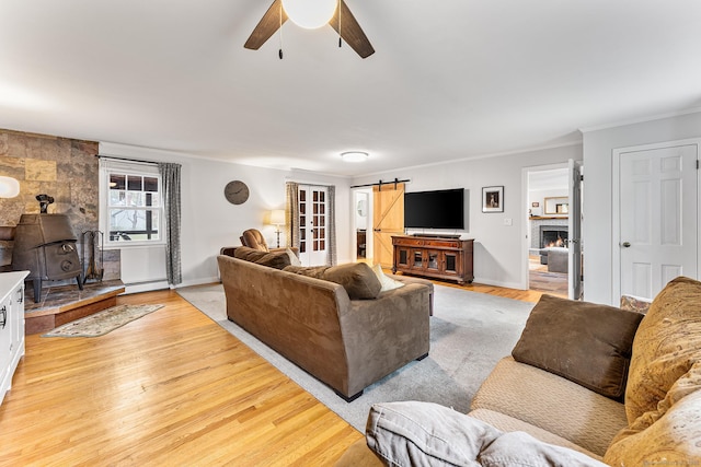 16 Howes Ln, Redding, CT 06896 - living area with a barn door, a wood stove, ceiling fan, light wood-style flooring, and a baseboard heating unit