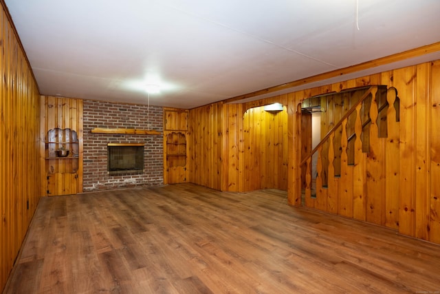 955 N Main St, West Hartford, CT 06117 - unfurnished living room featuring wood walls, wood finished floors, a fireplace, and stairs