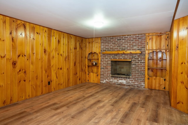 955 N Main St, West Hartford, CT 06117 - unfurnished living room with wood finished floors, wooden walls, and a brick fireplace