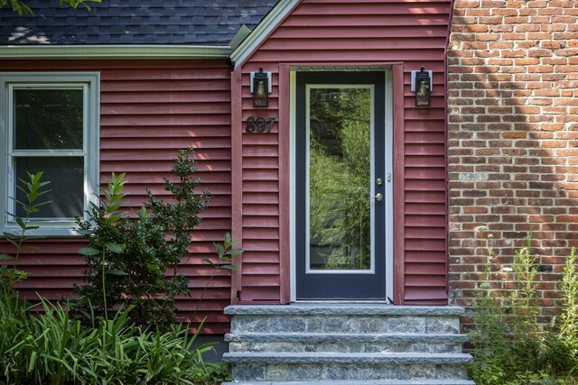 view of exterior entry with a shingled roof