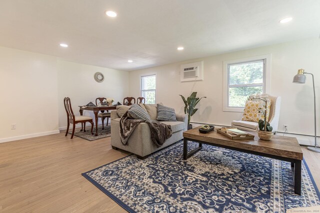 living area featuring recessed lighting, light wood-type flooring, a wall mounted air conditioner, and a baseboard radiator