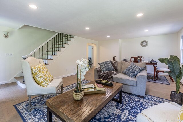 living area with baseboards, recessed lighting, wood finished floors, and stairway
