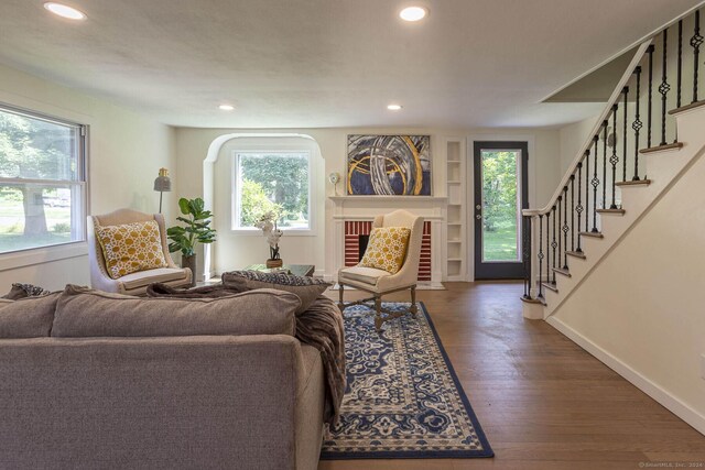 living room with built in features, recessed lighting, wood finished floors, and stairs