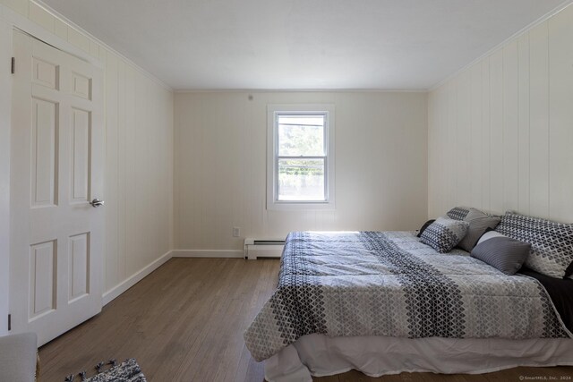 bedroom featuring baseboards, light wood finished floors, crown molding, and baseboard heating