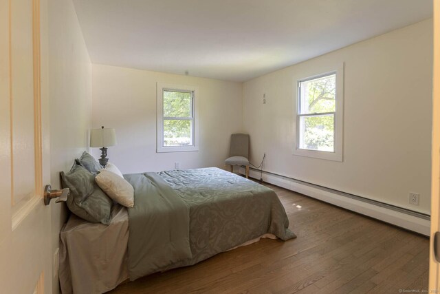 bedroom with a baseboard heating unit and wood finished floors