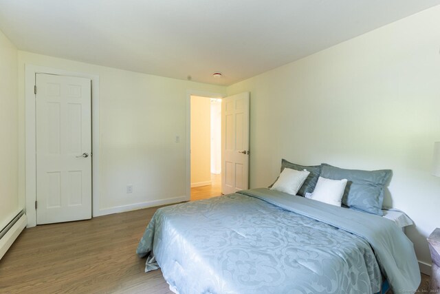 bedroom featuring baseboards, a baseboard radiator, and wood finished floors