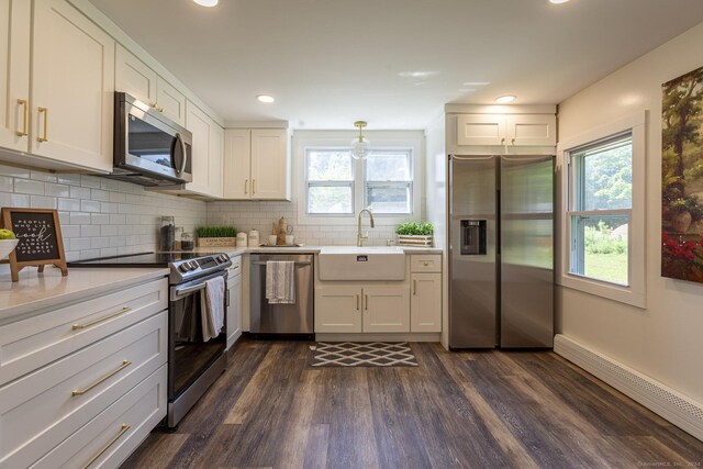 kitchen featuring decorative backsplash, dark wood-style flooring, appliances with stainless steel finishes, a sink, and light countertops