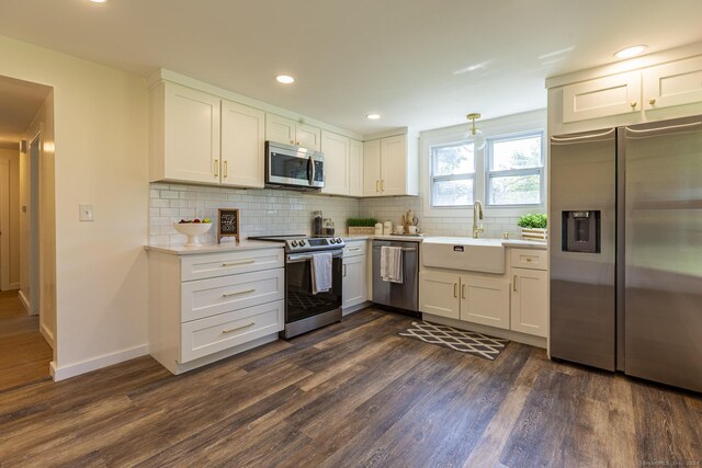 kitchen featuring white cabinets, dark wood-style flooring, appliances with stainless steel finishes, a sink, and light countertops