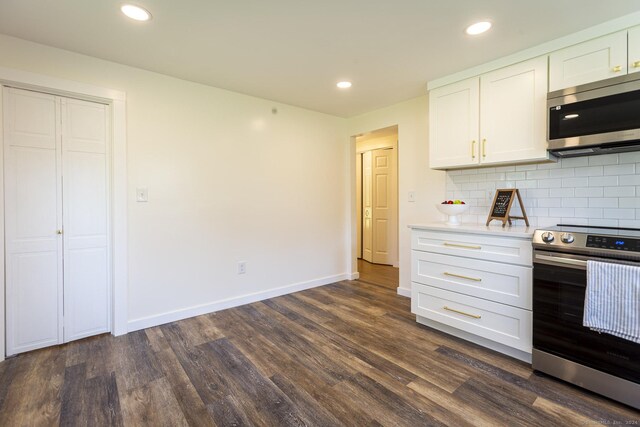 kitchen with dark wood-style flooring, light countertops, baseboards, stainless steel appliances, and white cabinetry