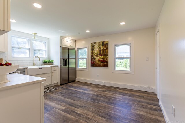 kitchen with dark wood finished floors, a healthy amount of sunlight, stainless steel fridge with ice dispenser, and tasteful backsplash
