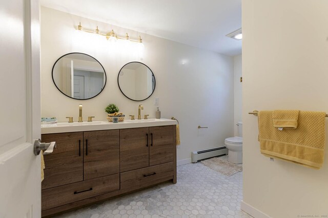 bathroom with a sink, a baseboard heating unit, toilet, and double vanity