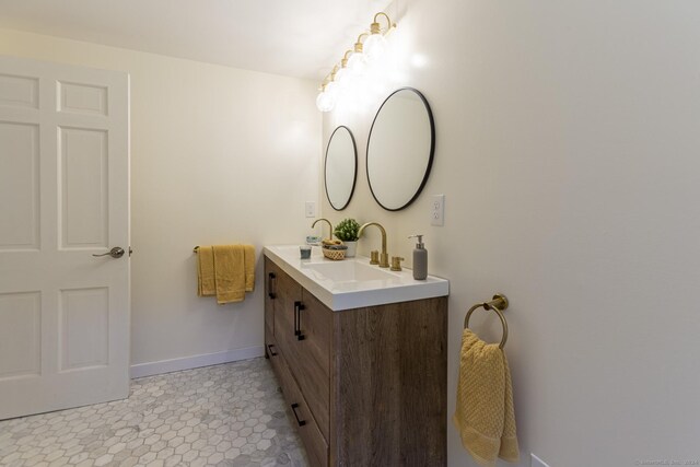 bathroom featuring a sink, baseboards, and double vanity