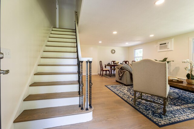 stairway with baseboards, a wall unit AC, recessed lighting, and wood finished floors