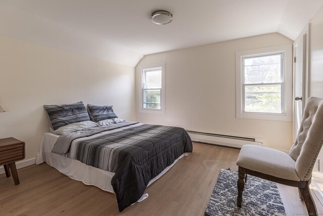 bedroom featuring baseboards, a baseboard radiator, wood finished floors, and vaulted ceiling