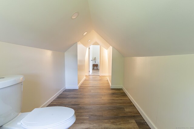 bathroom featuring baseboards, vaulted ceiling, toilet, and wood finished floors