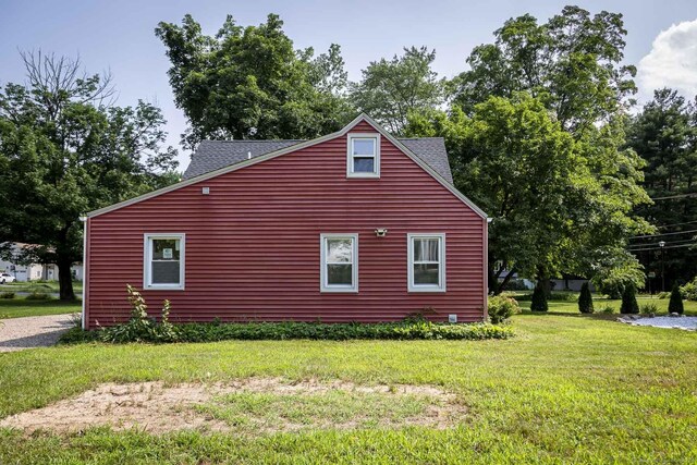 view of home's exterior with roof with shingles and a yard