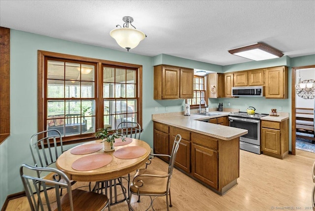 kitchen featuring appliances with stainless steel finishes, brown cabinets, and a textured ceiling