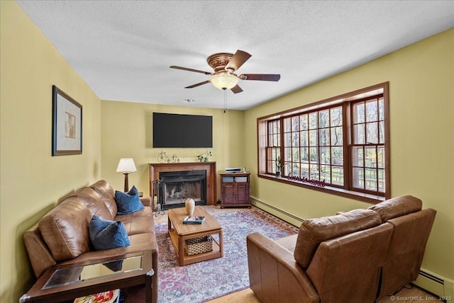 living area featuring a textured ceiling, ceiling fan, a baseboard heating unit, and a fireplace