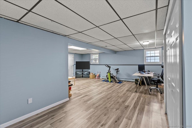 office space featuring baseboards, a drop ceiling, wood finished floors, and a wealth of natural light
