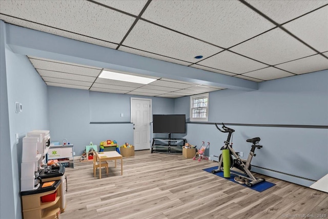 recreation room with a drop ceiling, wood finished floors, and a baseboard radiator
